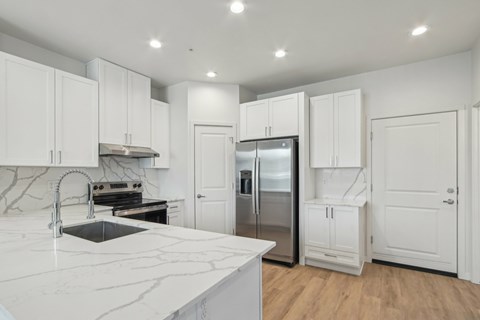 A kitchen with white cabinets and a marble countertop.