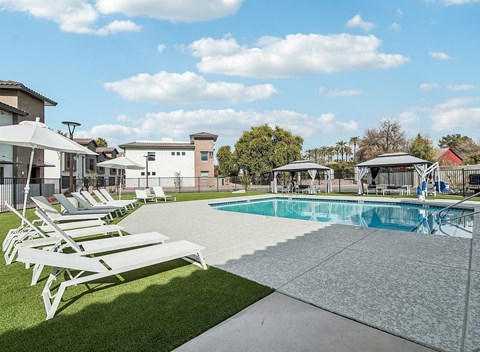 A pool with sun loungers in front of a building.