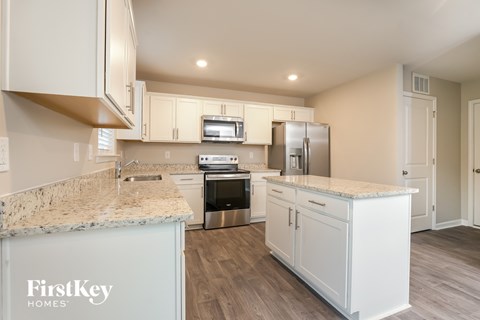 A kitchen with a granite counter top and a refrigerator.