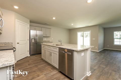 A kitchen with a stainless steel dishwasher and white cabinets.