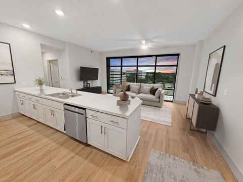 A modern kitchen with white cabinets and a wooden floor.