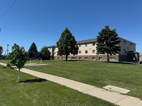 A grassy area in front of a building with a sign that reads "Crimson".