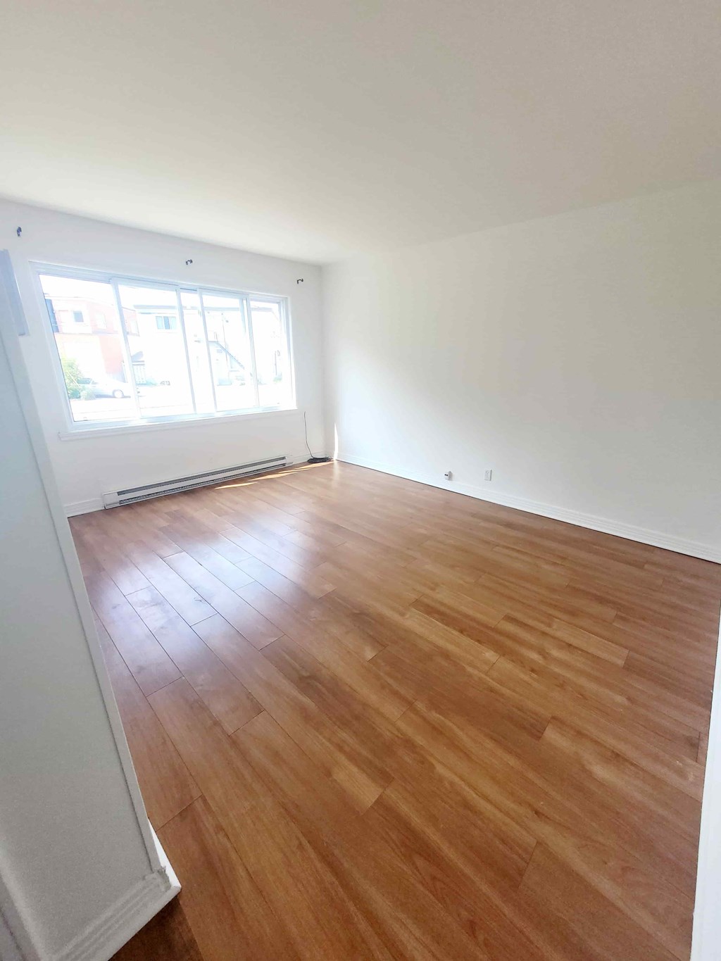 A room with wooden flooring and a window.