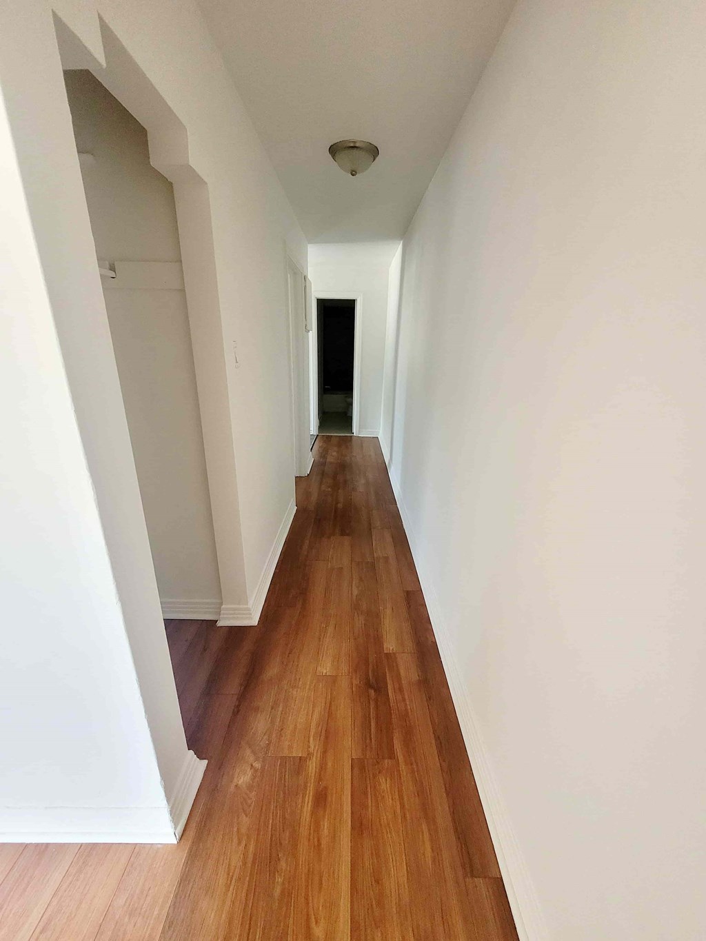 A long hallway with wood floors and white walls.
