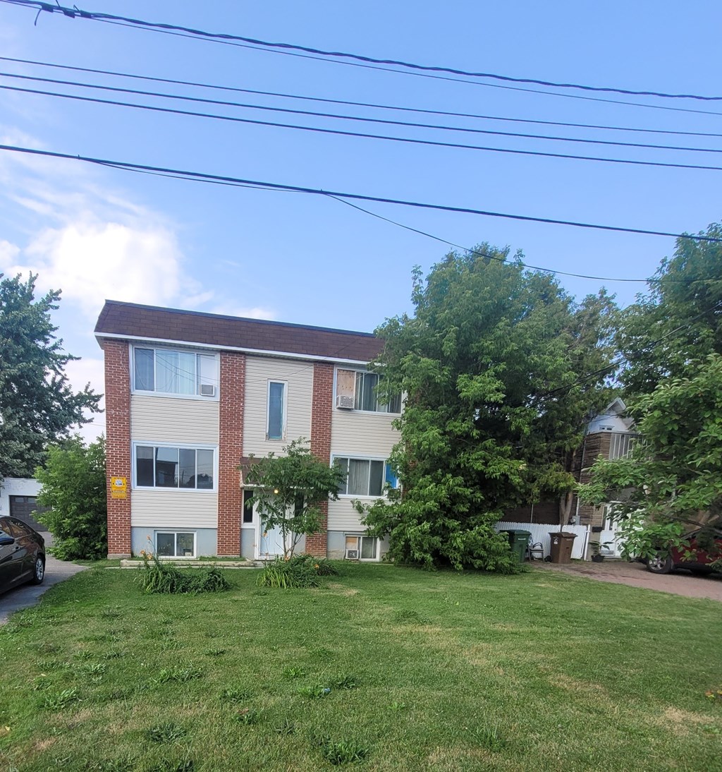 A building with a brown roof and white walls with a yellow sign on the side.