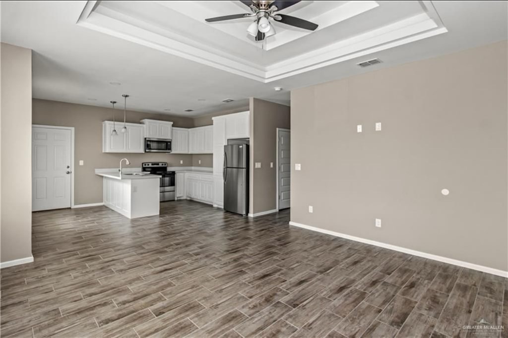 A spacious kitchen with a refrigerator, microwave, oven, and sink.
