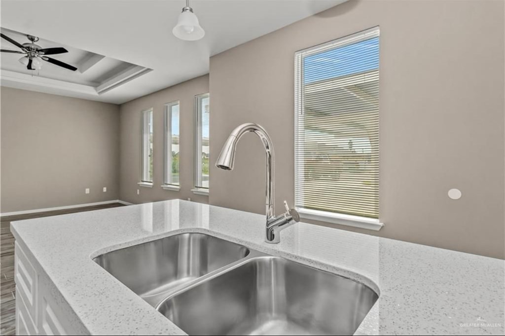 A modern kitchen with a stainless steel sink and a ceiling fan.