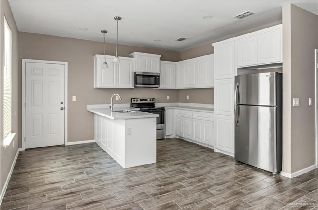 A kitchen with white cabinets and a wooden floor.
