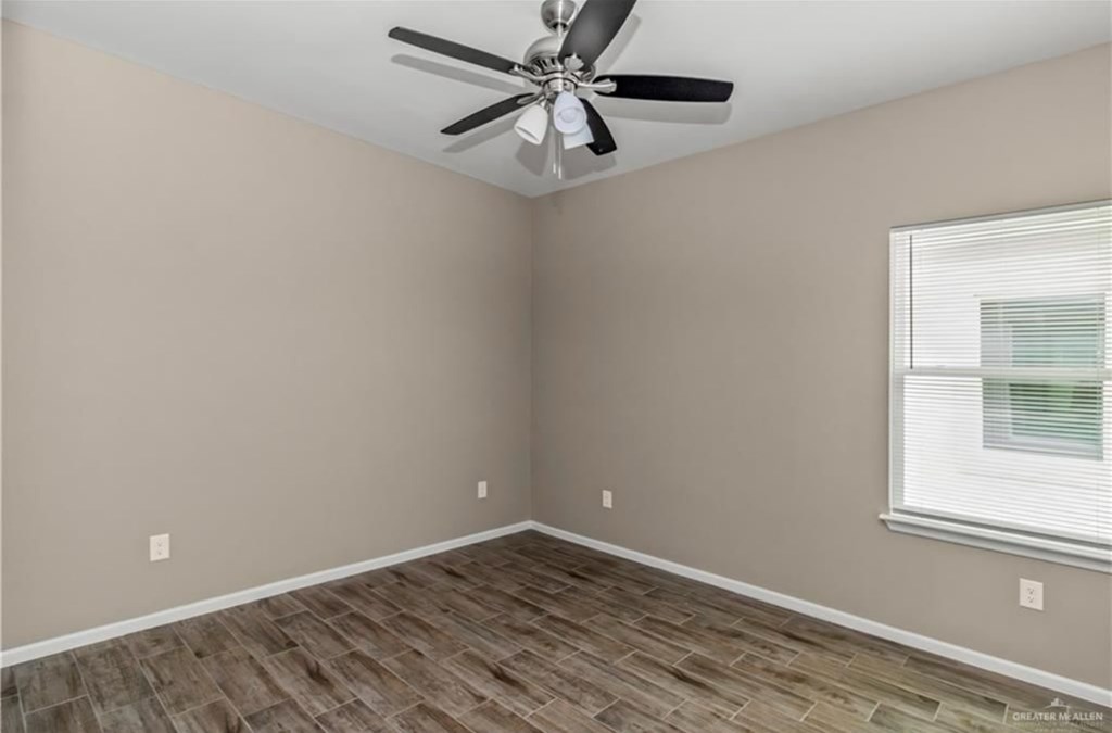 A room with a ceiling fan and a window with blinds.