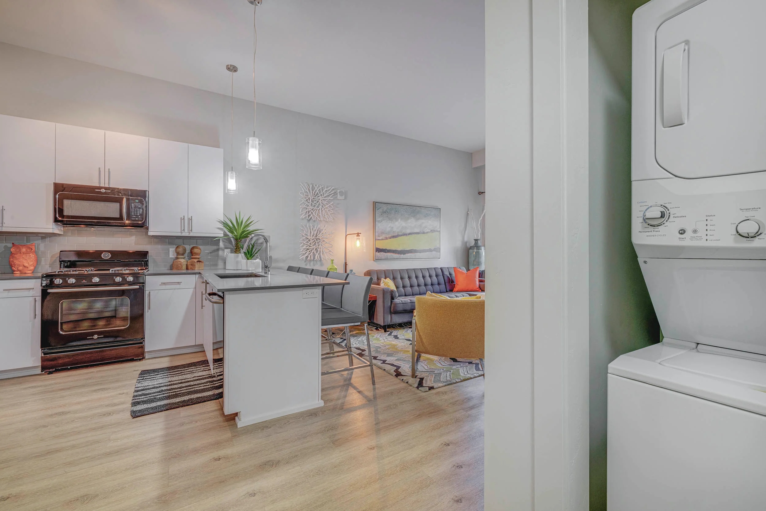 A modern kitchen with white appliances and wooden floors.