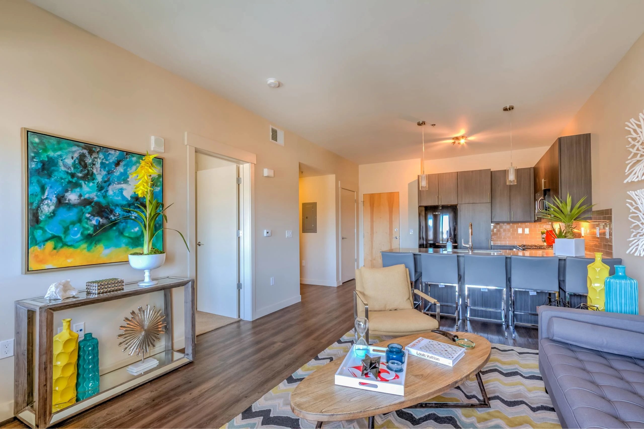 A modern living room with a wooden floor and a large painting on the wall.