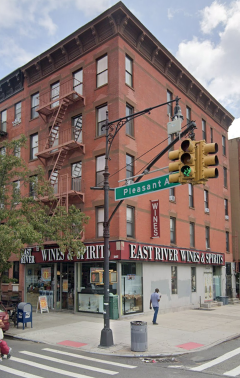 A street corner with a traffic light and a building with a sign that says East River Wines & Spirits.