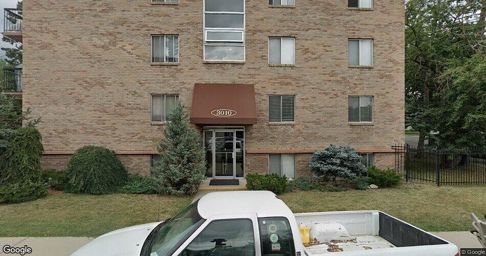 A white truck is parked in front of a brick building.