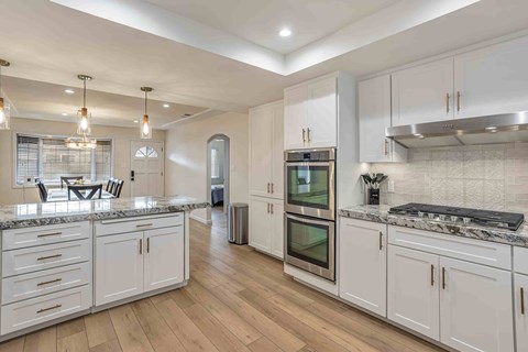A kitchen with white cabinets and a marble countertop.