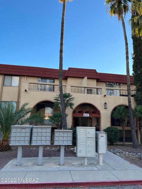 A building with a red roof and palm trees in front.