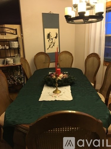 A dining table with a green tablecloth and a white tablecloth underneath it.