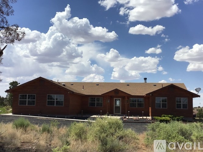 A house with a brown roof and a brown door is in front of a cloudy sky.