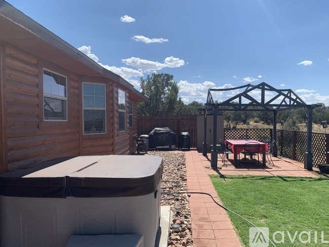 A wooden cabin with a hot tub and a black metal structure in the backyard.