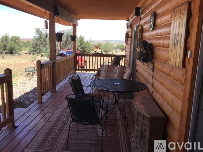 A wooden deck with a table and chairs overlooking a field.