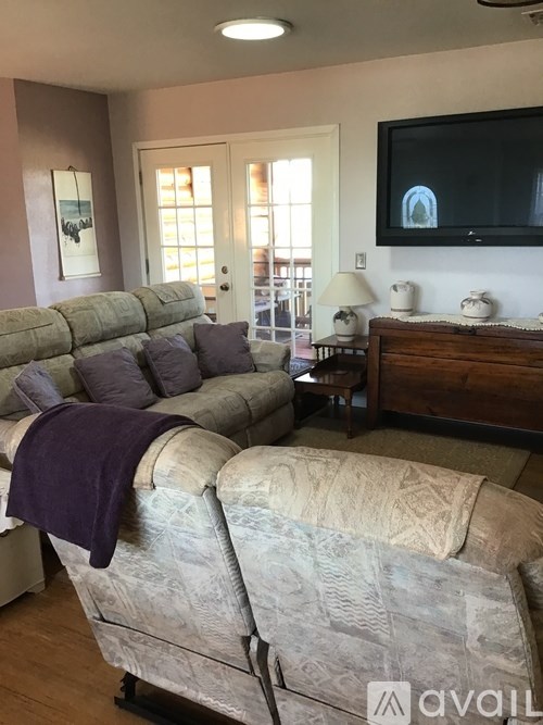 A living room with a grey couch and a television mounted on the wall.