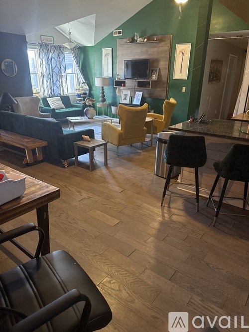 A living room with a green wall and a wooden floor.