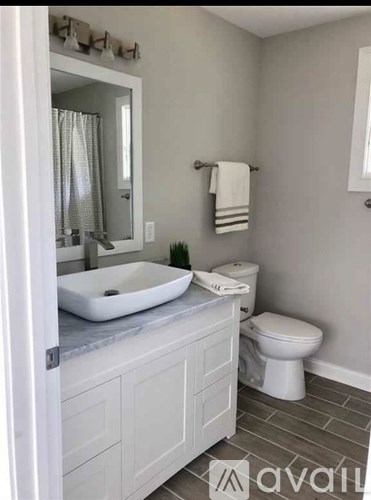 A bathroom with a toilet, sink, and mirror.