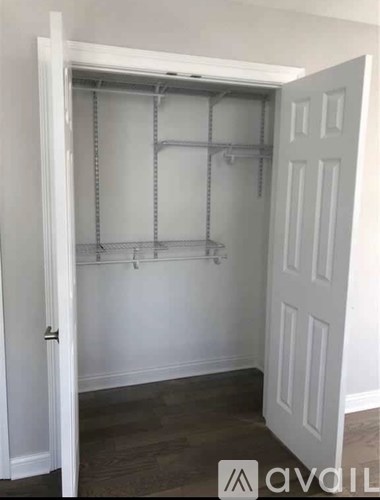 A white door is open to a room with a grey floor and a white wall.