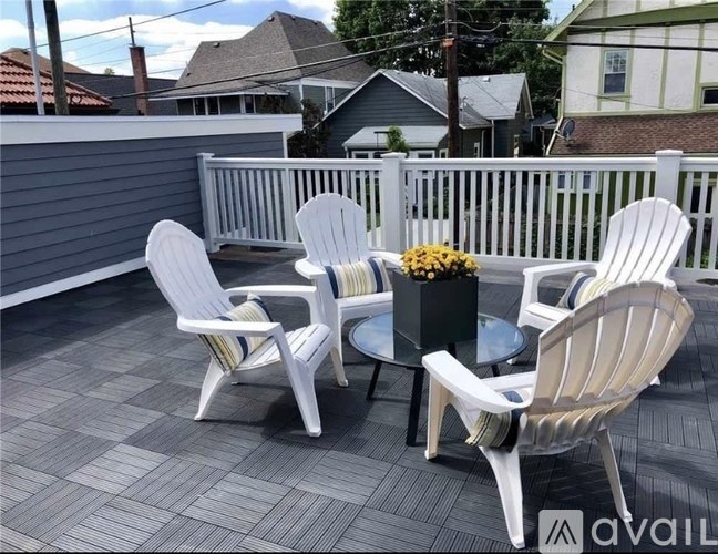 A patio with a white table and chairs and a vase of yellow flowers.