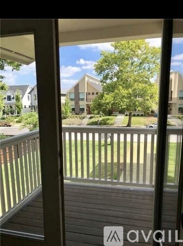 A view from a balcony looking out at a grassy area and a building.