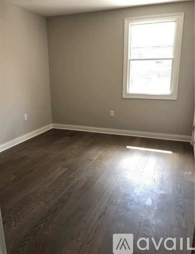 A room with a window and wooden flooring.