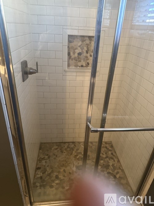 A shower with a glass door and a tiled floor.