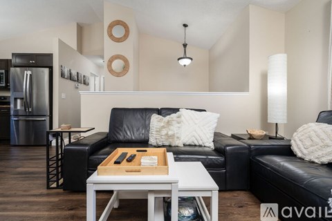 A modern living room with a black leather couch and a white coffee table.