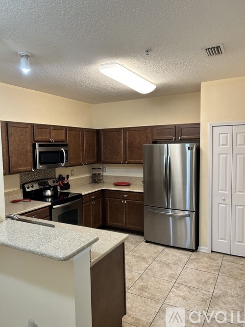 A kitchen with a refrigerator, microwave, and oven.