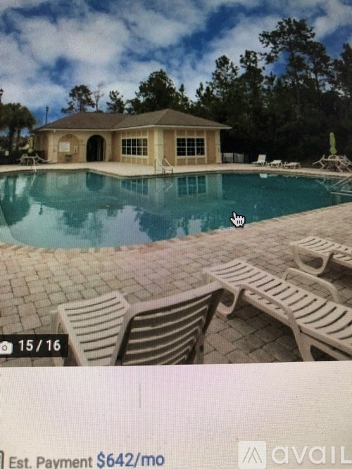 A pool with a house and a chair in the foreground.