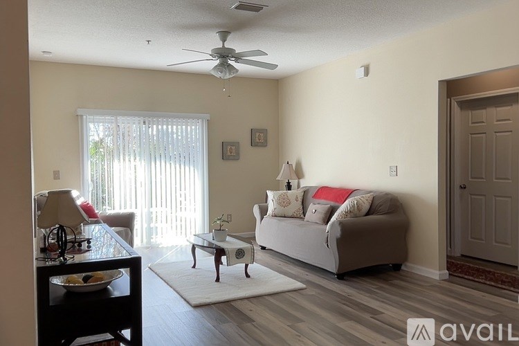 A living room with a grey couch, a coffee table, and a ceiling fan.