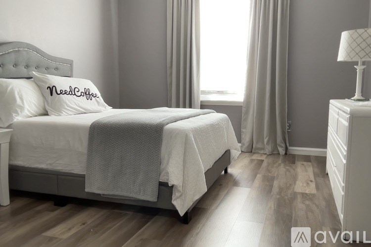 A bedroom with a bed, nightstand, and window.