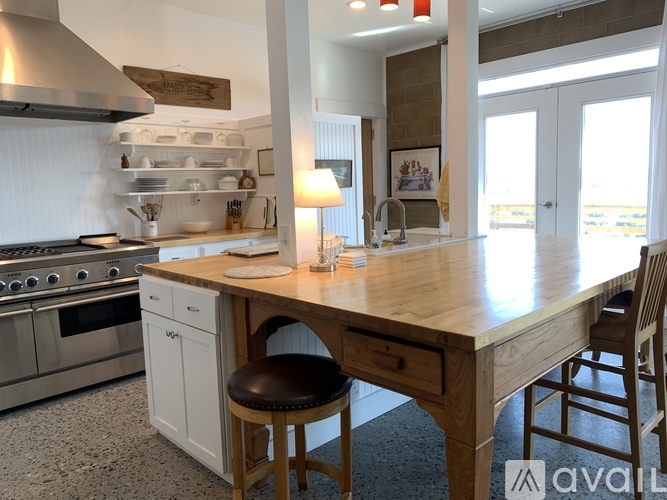 A kitchen with a wooden island and stainless steel appliances.