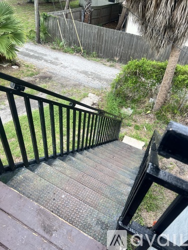 A staircase with a black railing leads down to a path.