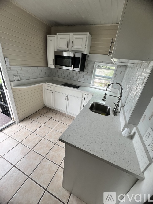 A kitchen with white cabinets and a grey countertop.