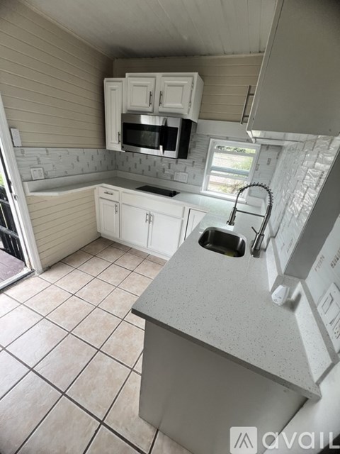 A kitchen with white cabinets and a grey countertop.