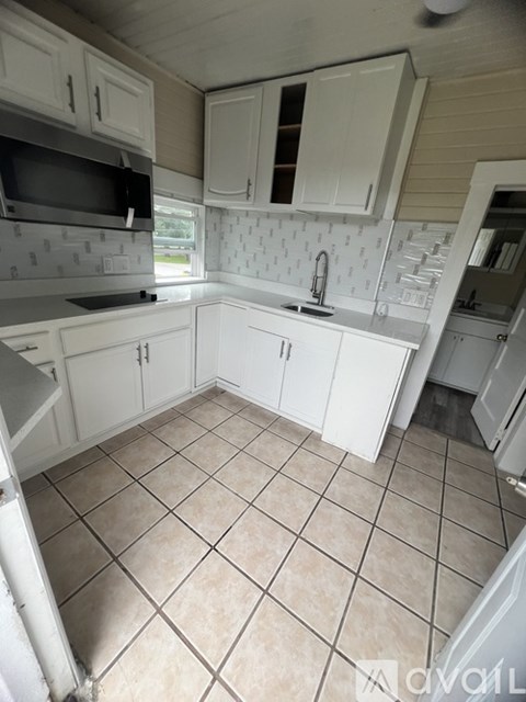 A kitchen with white cabinets and a tiled floor.