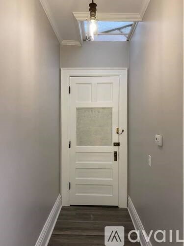 A white door with a glass panel is in the middle of a hallway.