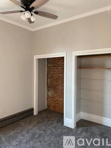 A room with a ceiling fan and a brick wall.