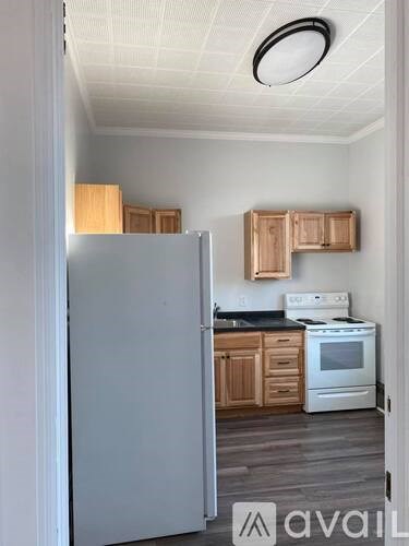 A kitchen with a white refrigerator and wooden cabinets.