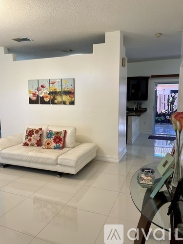 A living room with a white couch and a painting on the wall.