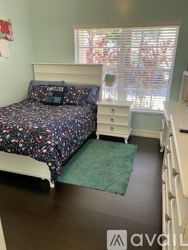 A bedroom with a bed, nightstand, and window with blinds.