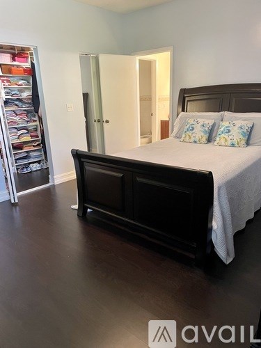 A bedroom with a large bed and a refrigerator in the corner.