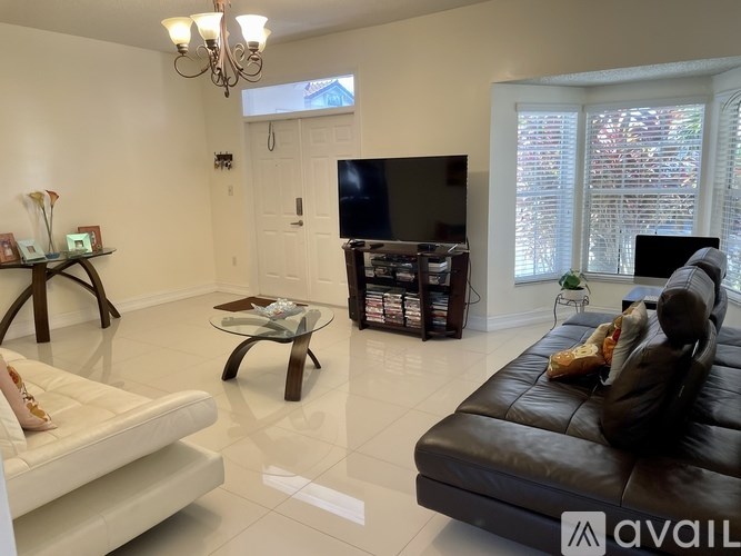A living room with a black leather couch and a white sofa.