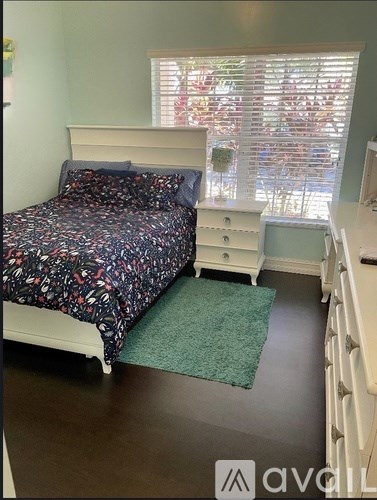 A white shelving unit with multiple shelves is empty and stands against a white wall.