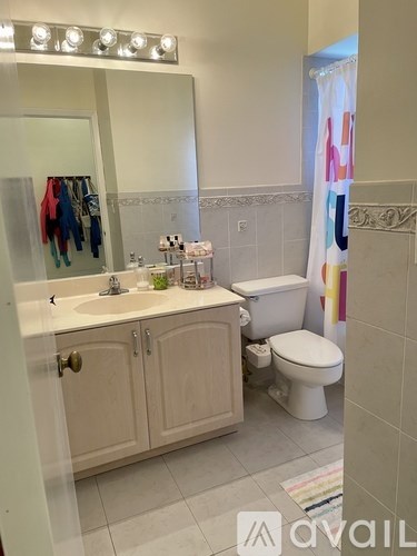 A bathroom with a toilet, sink, and mirror.